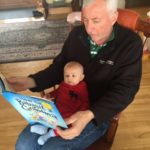 Older man reading to newborn